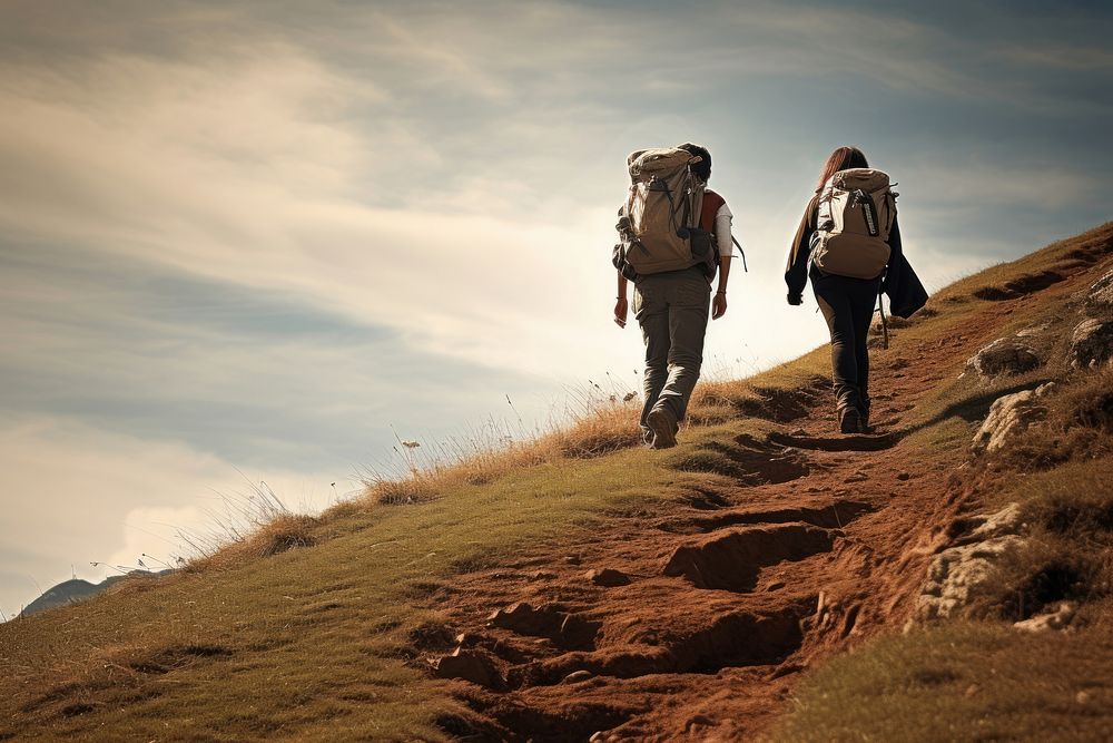 Two people hiking with backpack along a hillside photography recreation adventure.