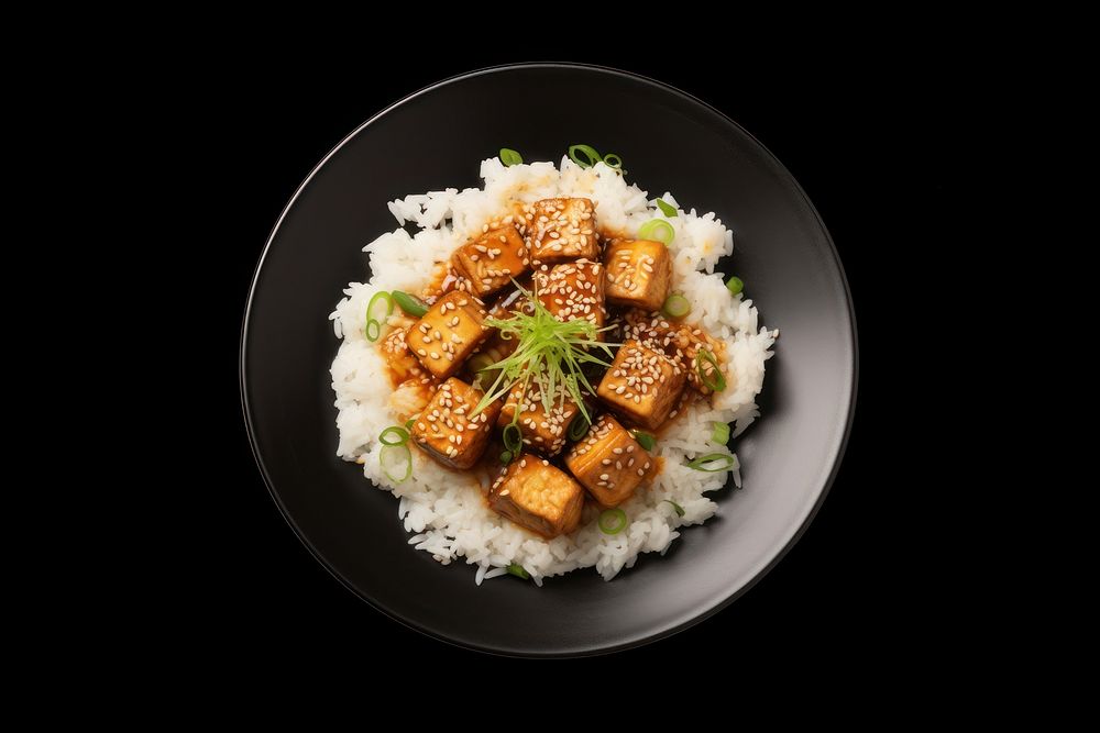 A rice and fried tofu with sesame seeds on the black plate food meat vegetable.