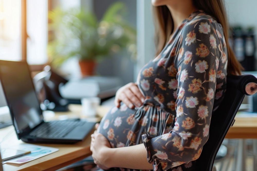 Pregnant woman working in the office furniture computer sitting.