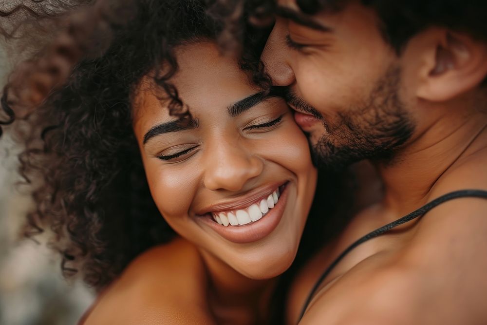 Woman kissing her smiling boyfriend on a cheek laughing happy affectionate.