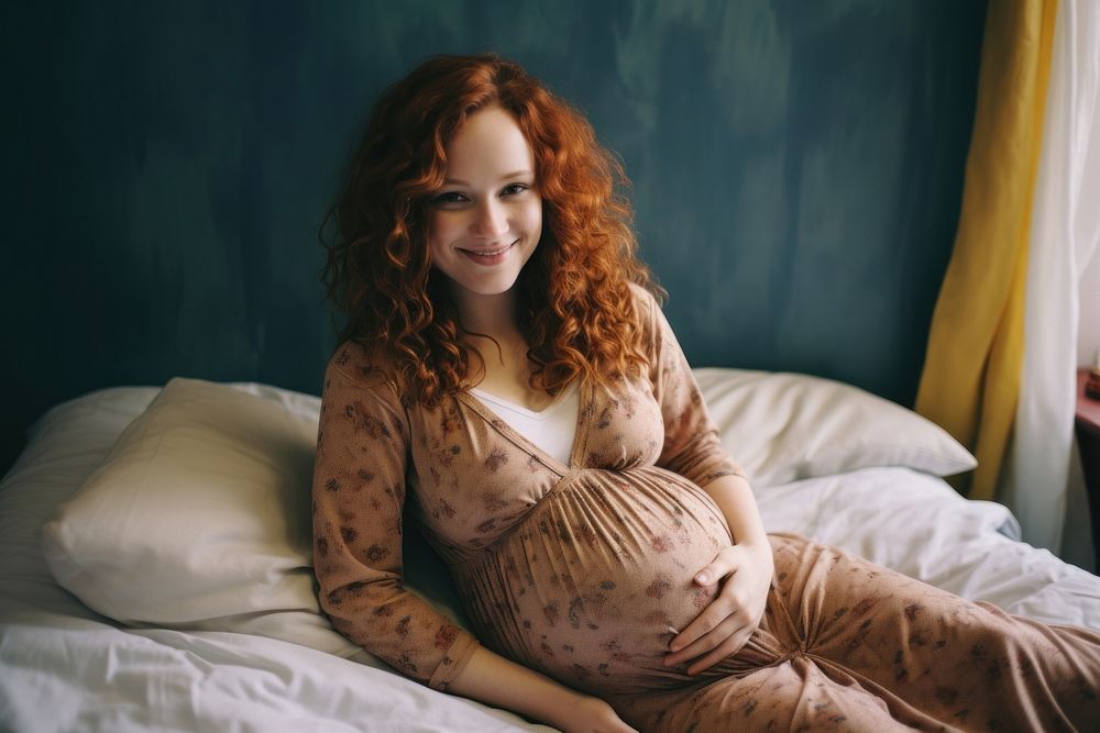 Young woman sits on bed holding pregnant belly furniture portrait adult.