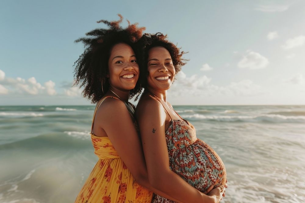 Happy black pregnant woman standing with mother at beach laughing portrait adult.