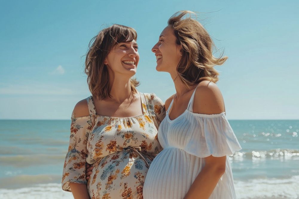 Happy pregnant woman standing with mother at beach laughing adult happy.