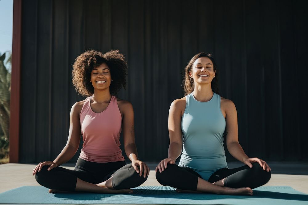 Two African American women yoga sitting sports.