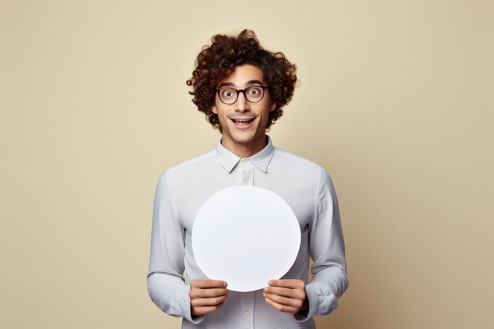 Young man holding empty speech bubble paper surprised portrait glasses.