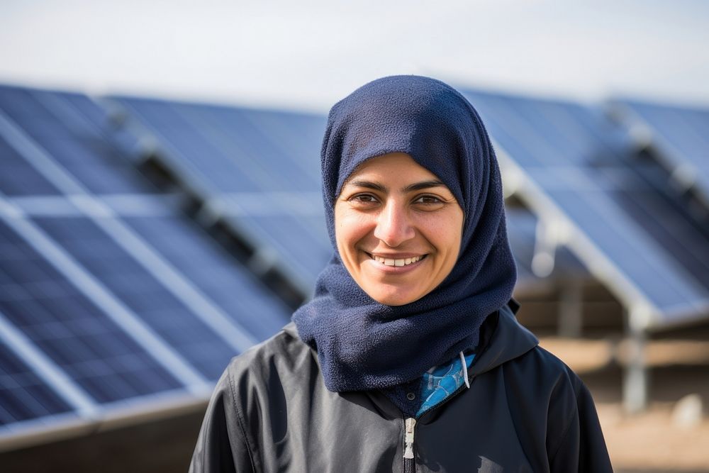 A solar Iranian woman worker smiles in front of solar panels happy environmentalist architecture.