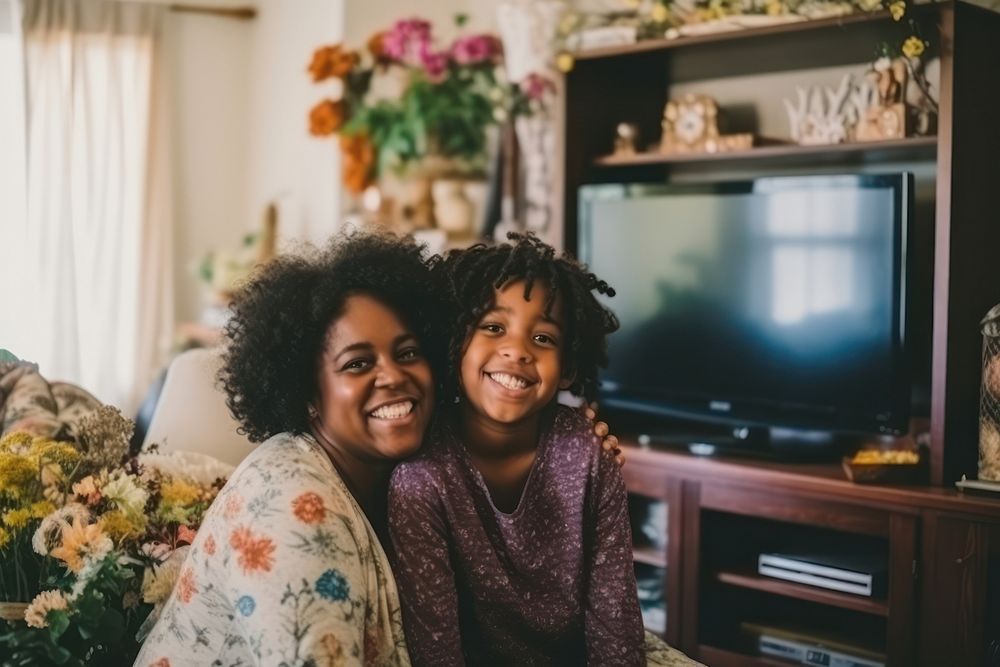 Daily life of black mom and daughter wacthing TV in the room family adult happy.