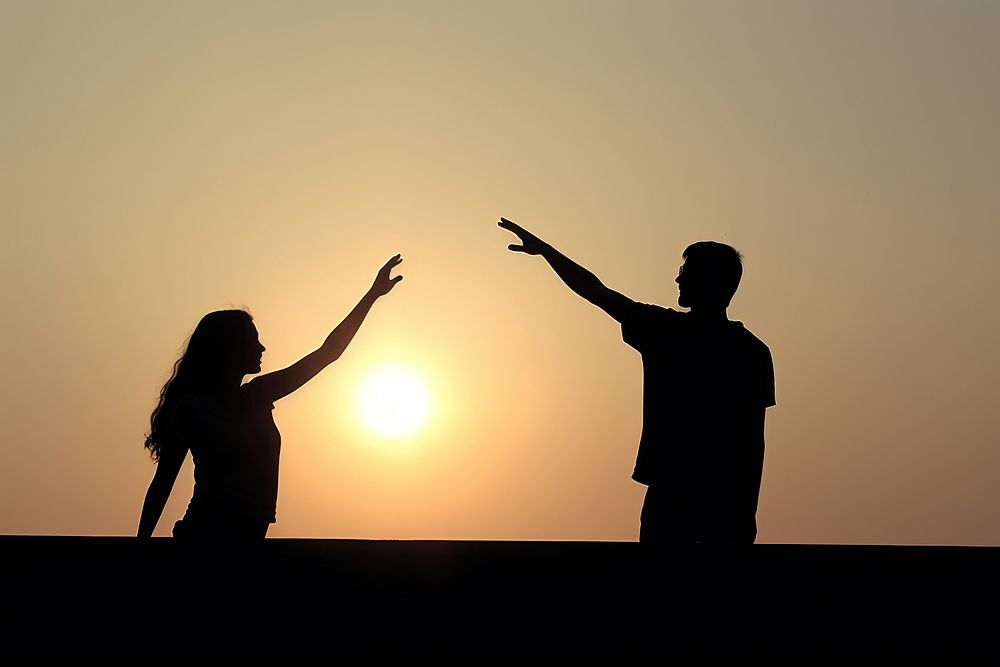 Silhouettes of two people backlighting adult sky.