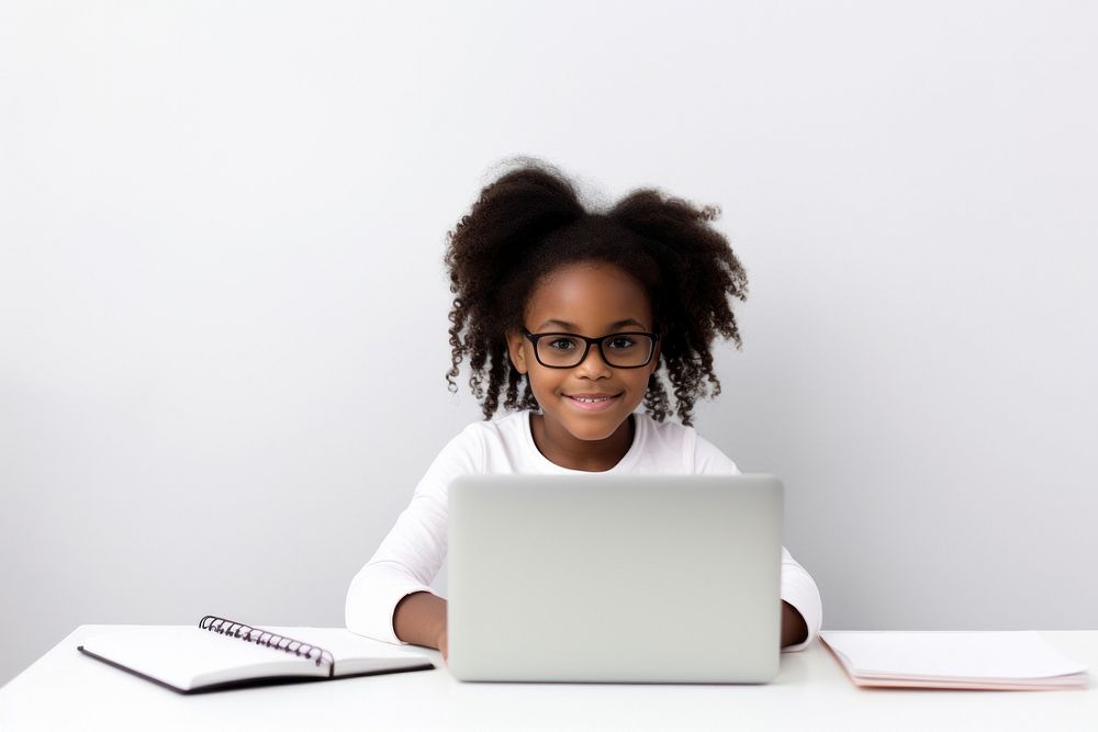 American girl kid sitting in font of laptop computer glasses writing.
