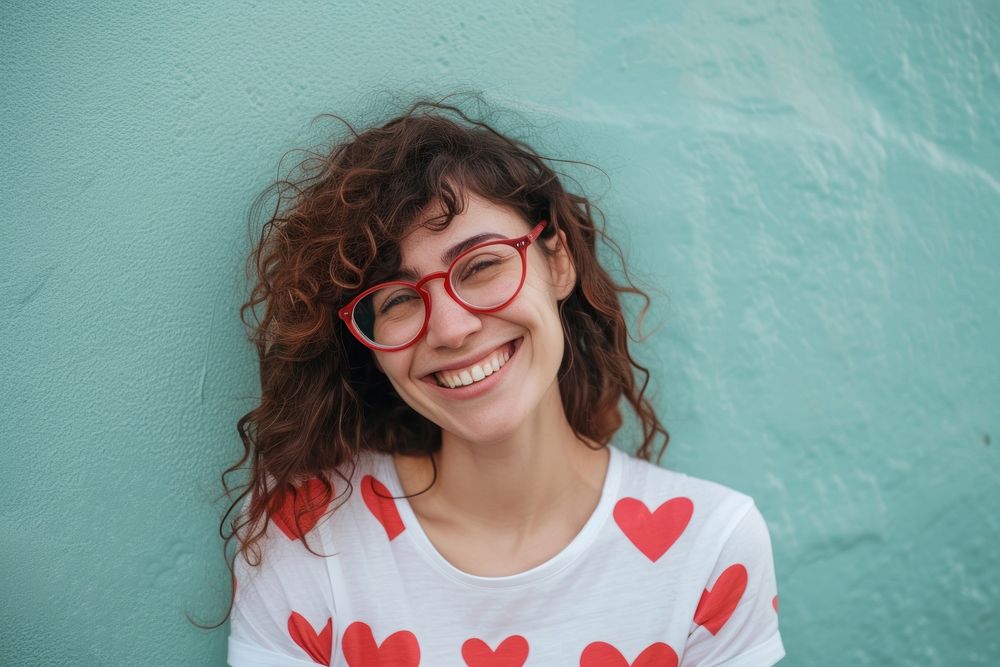Woman wearing heart-shaped matching shirts portrait glasses smiling.