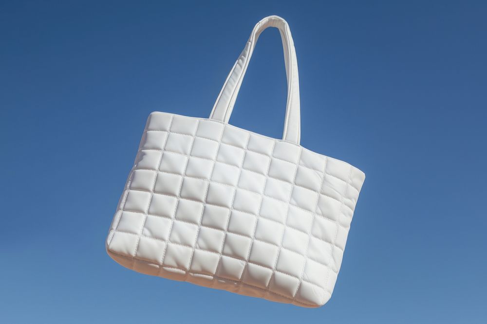 Hands holding white quilted totebag handbag purse blue.