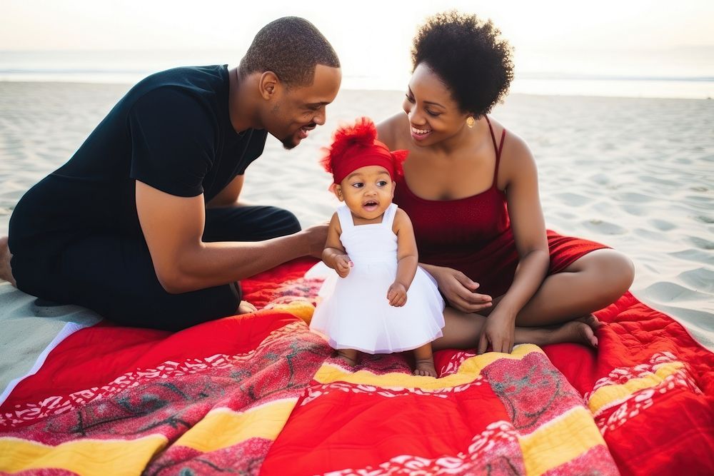 Black family on a beach mat with a baby in towel photography outdoors portrait.