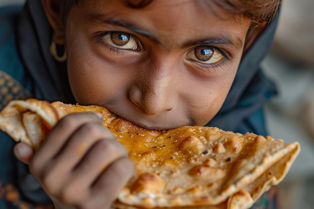 Indian boy eating food biting pizza.