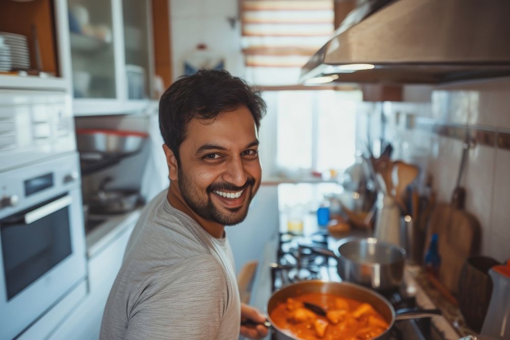 Indian father cooking food smiling kitchen.