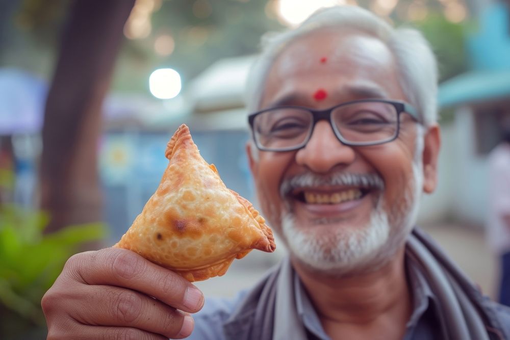 Indian uncle eating food glasses smiling.