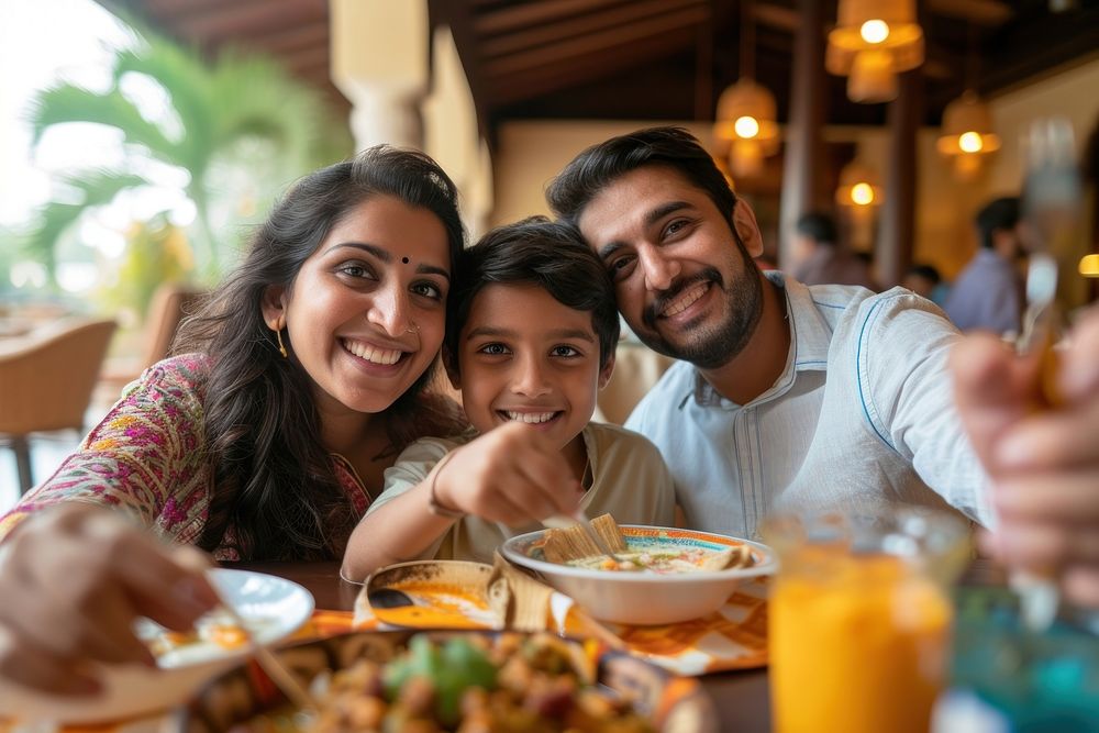 Indian family eating food restaurant smiling.