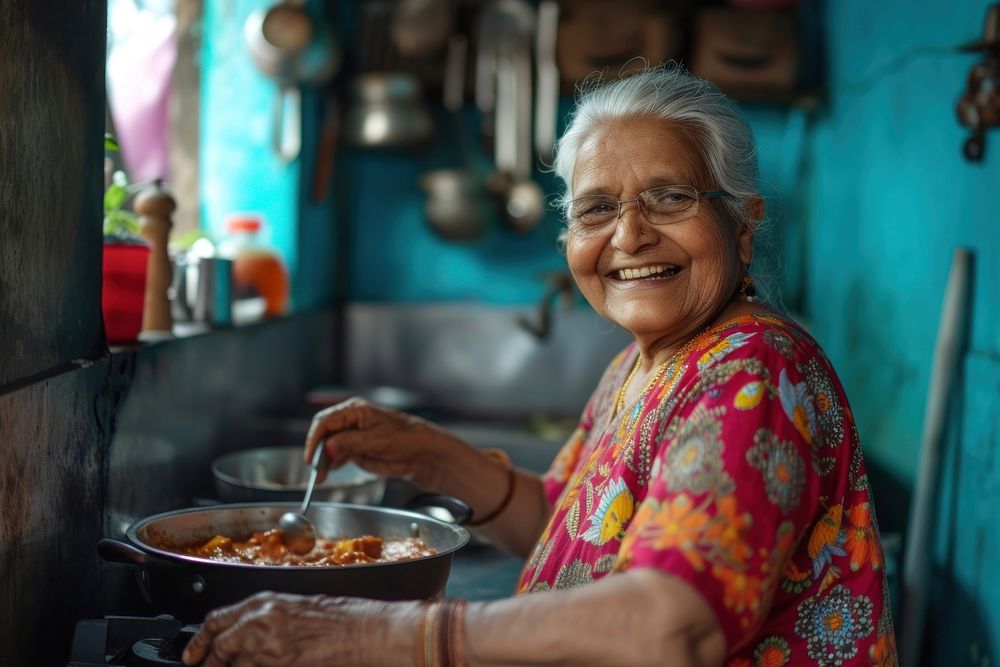 Indian grandmother cooking food smiling adult.