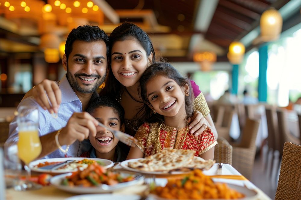 Indian family eating food restaurant smiling.