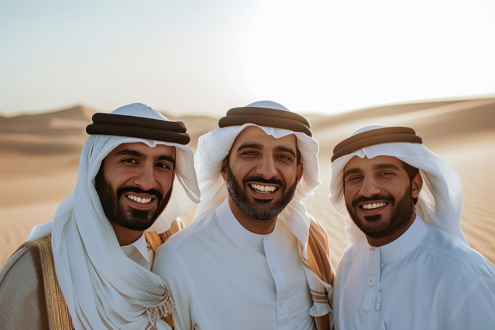 3 Middle eastern men in thawb outdoors smiling desert.