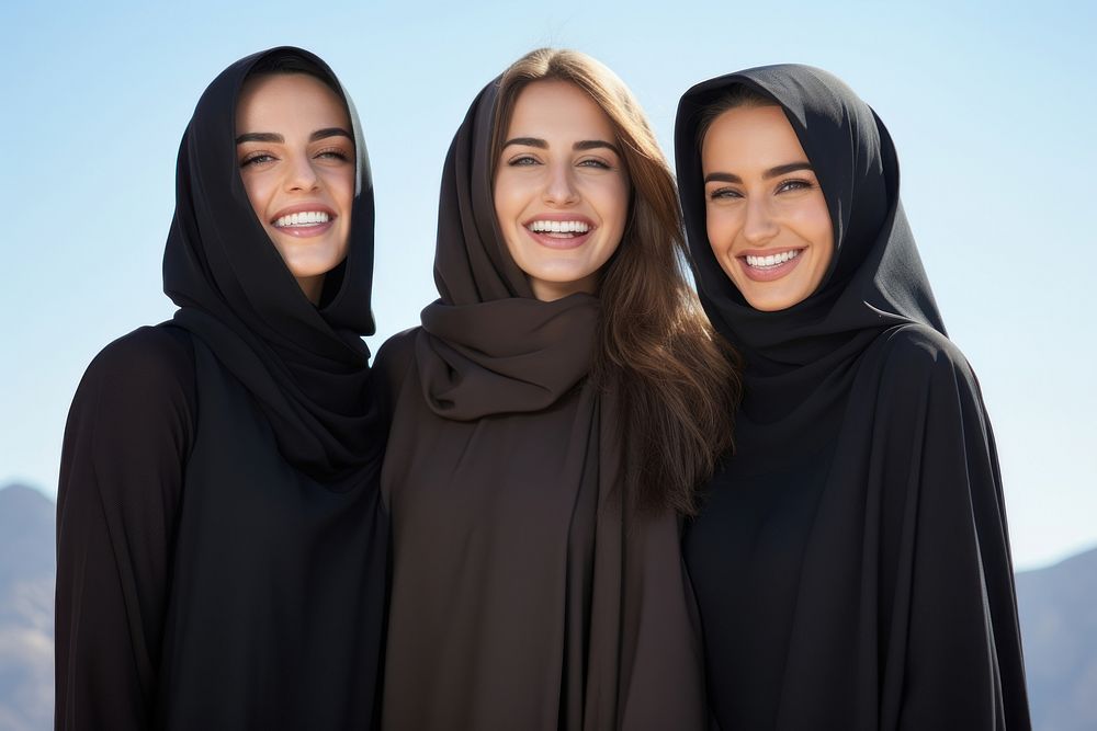 3 Middle eastern women laughing outdoors smiling.