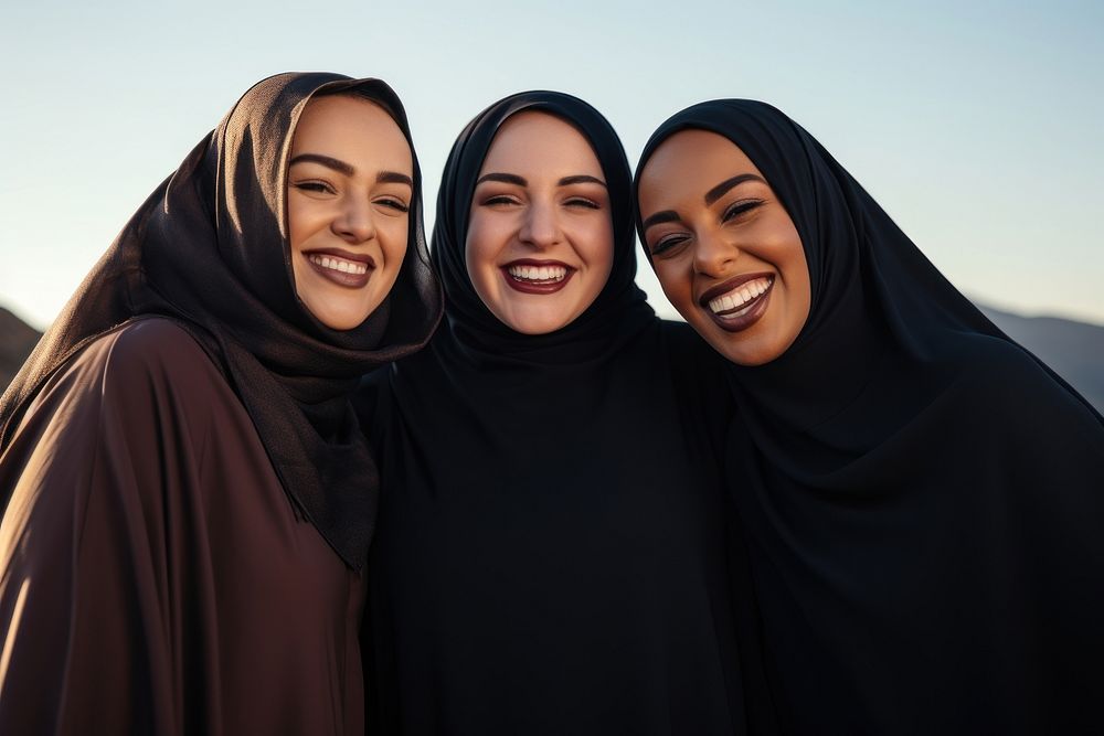 3 plus size Middle eastern women laughing outdoors smiling.