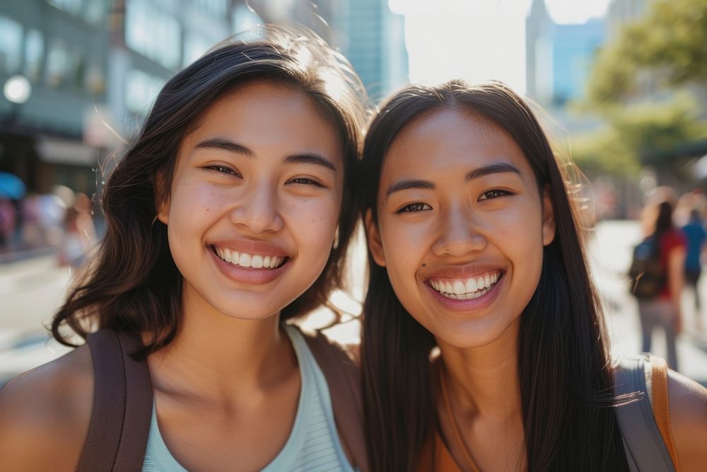 Two asian mixed race woman laughing outdoors smiling.