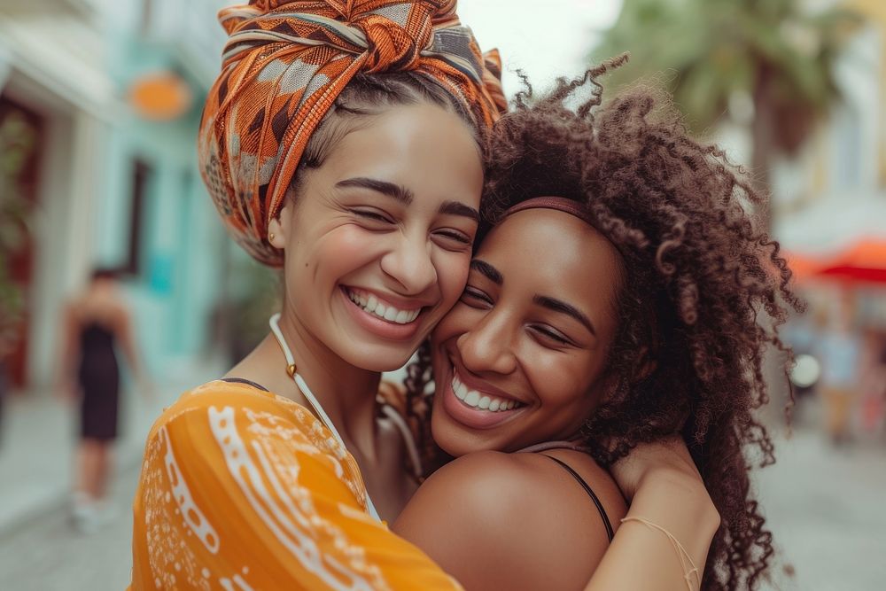 Two happy beautiful young African American women laughing hugging summer.
