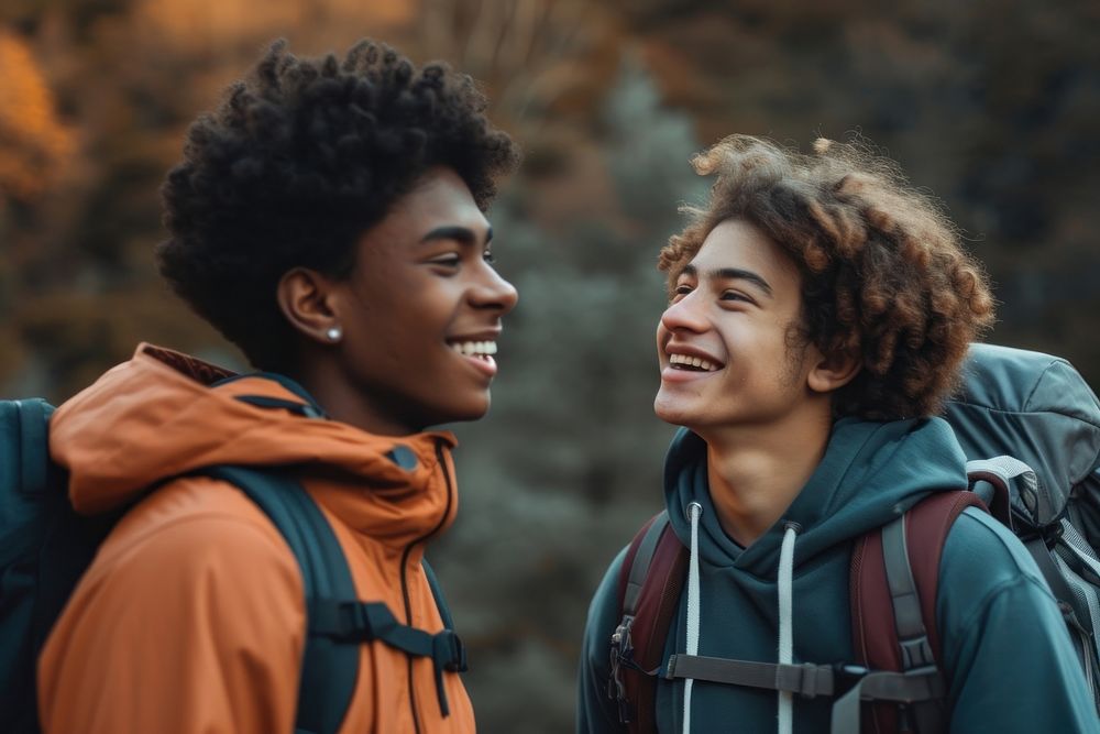 Mixed race teen men laughing outdoors smiling.