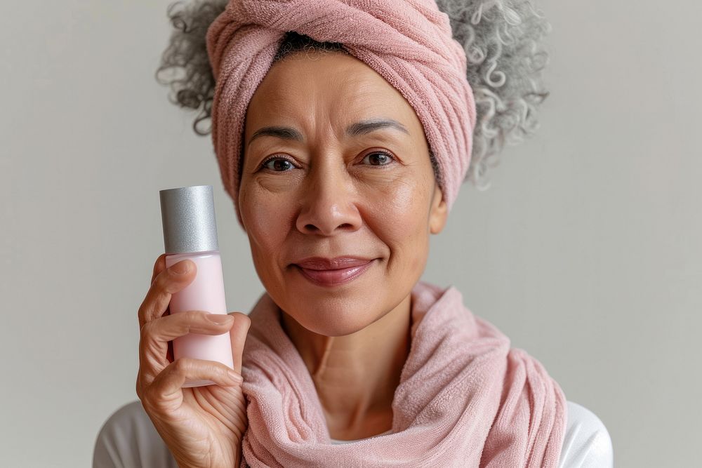 Multiracial senior woman holding a skincare bottle cosmetics happiness portrait.