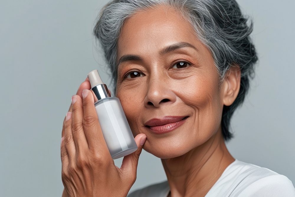 Multiracial senior woman holding a skincare bottle happiness cosmetics portrait.