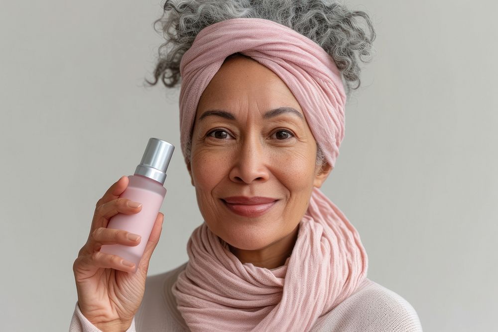 Multiracial senior woman holding a skincare bottle cosmetics scarf adult.