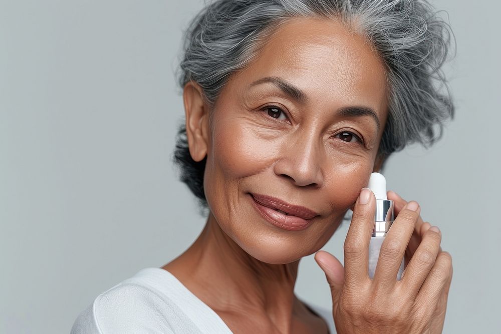 Multiracial senior woman holding a skincare bottle adult happiness cosmetics.