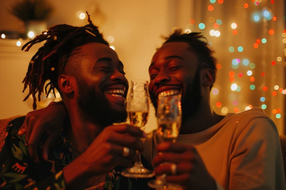 African American gay couple champagne laughing drinking.