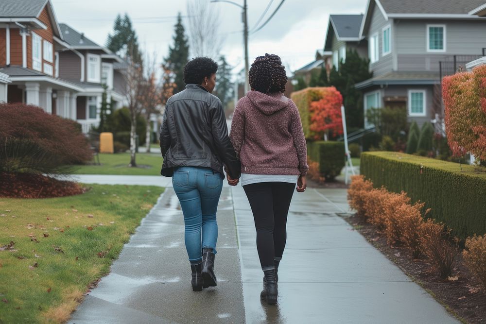 African American Lesbian couple walking in residential neighborhood footwear adult togetherness.