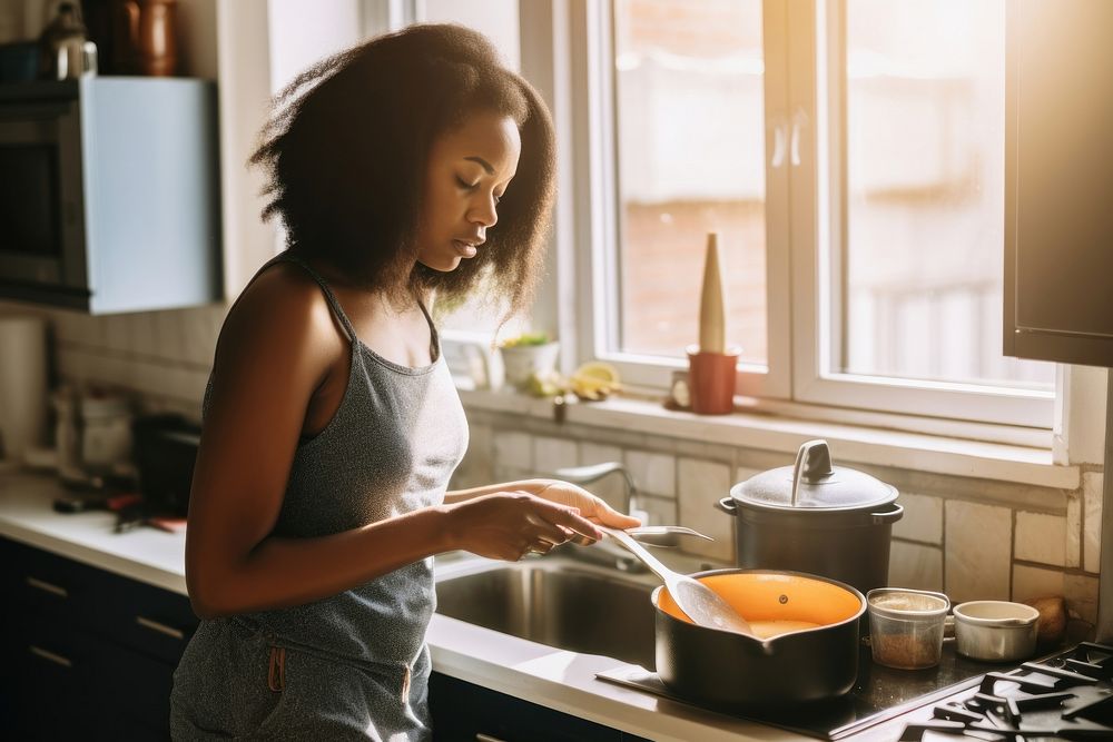 African American young woman cooking kitchen sink.