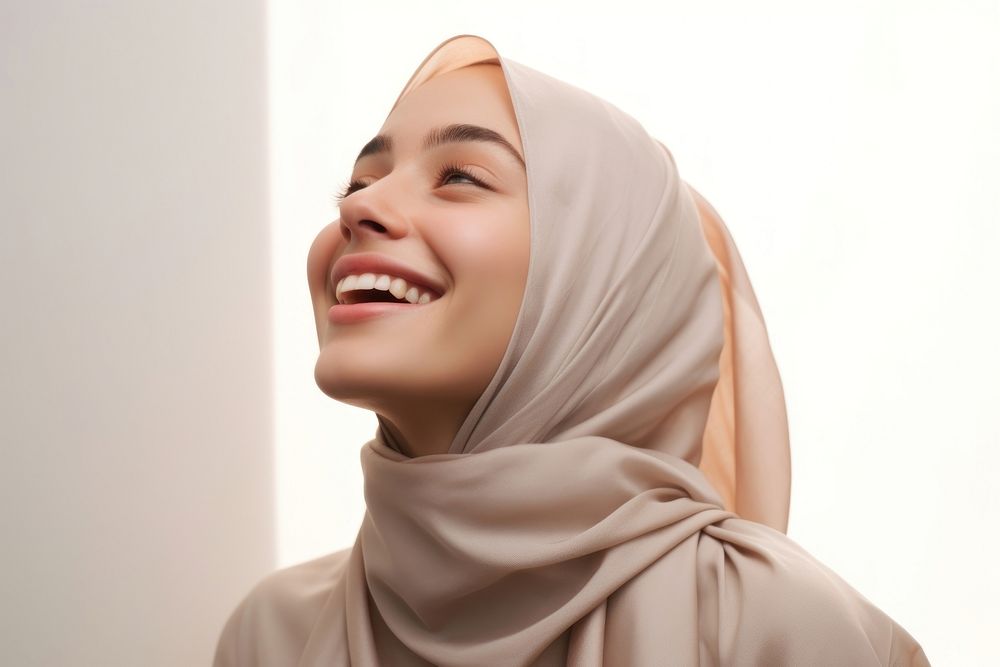 Middle eastern teen woman in abaya and hijab laughing looking adult.