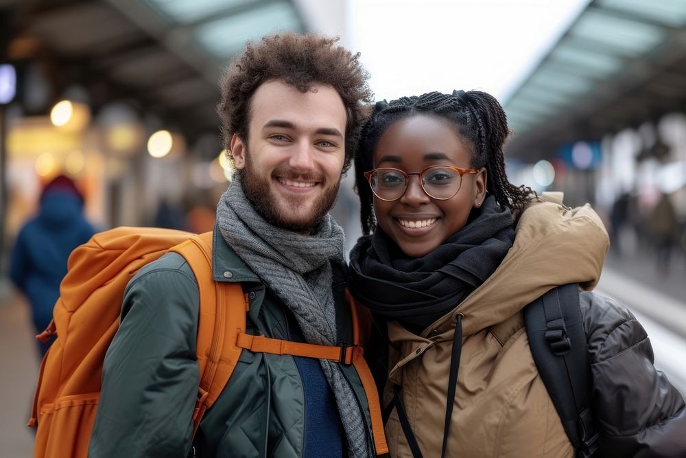 Mixed race couple with backpack smiling travel jacket.