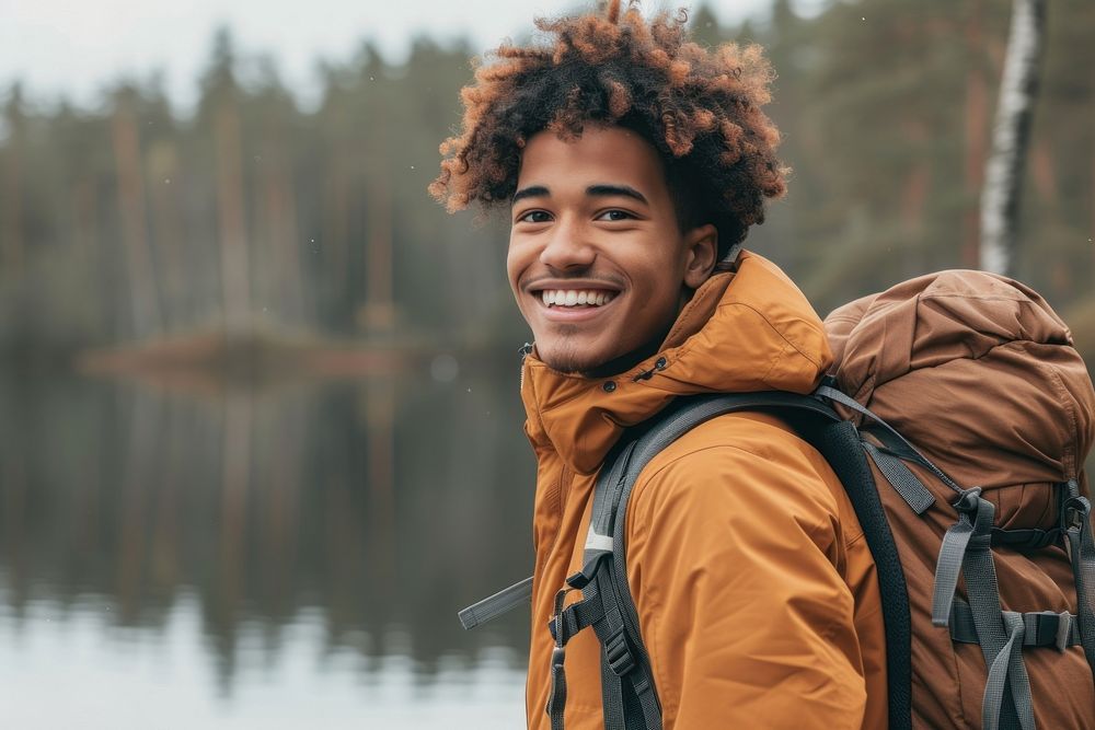 Mixed race teen man backpack outdoors smiling.