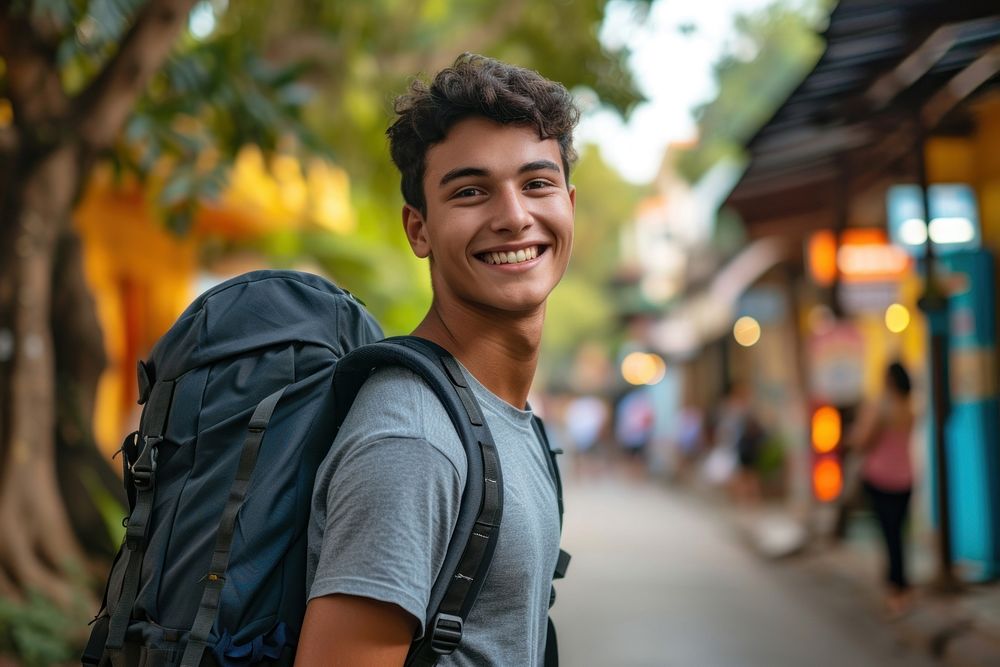 Mixed race teen man backpack outdoors smiling.
