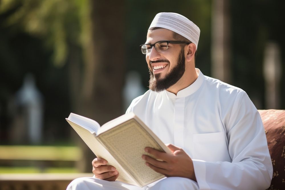 Muslim man wearing glasses and thawb book publication outdoors.