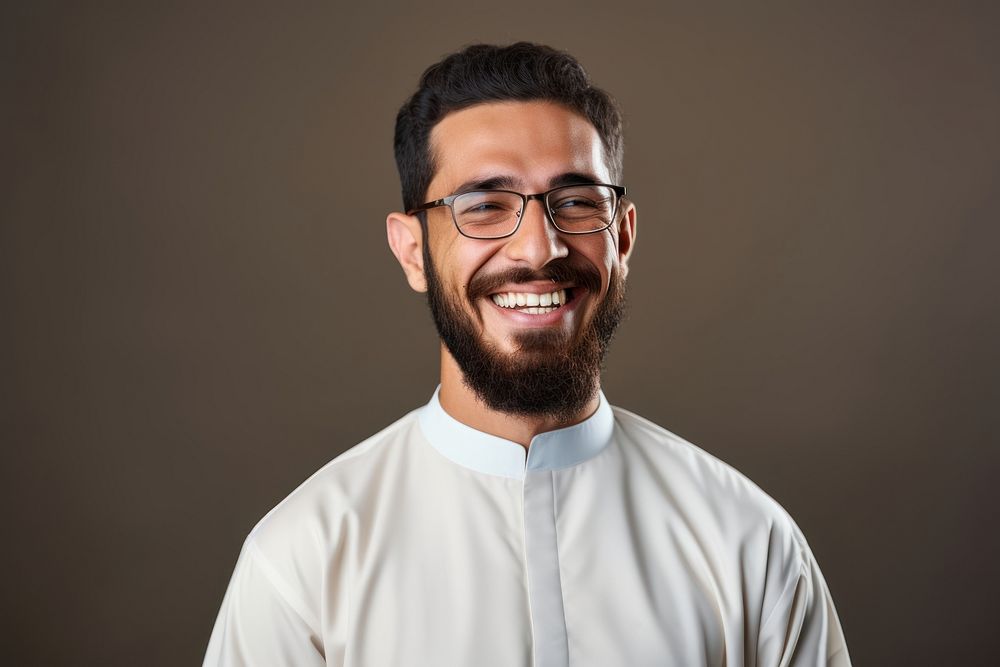 Muslim man wearing glasses and thawb smiling adult smile.