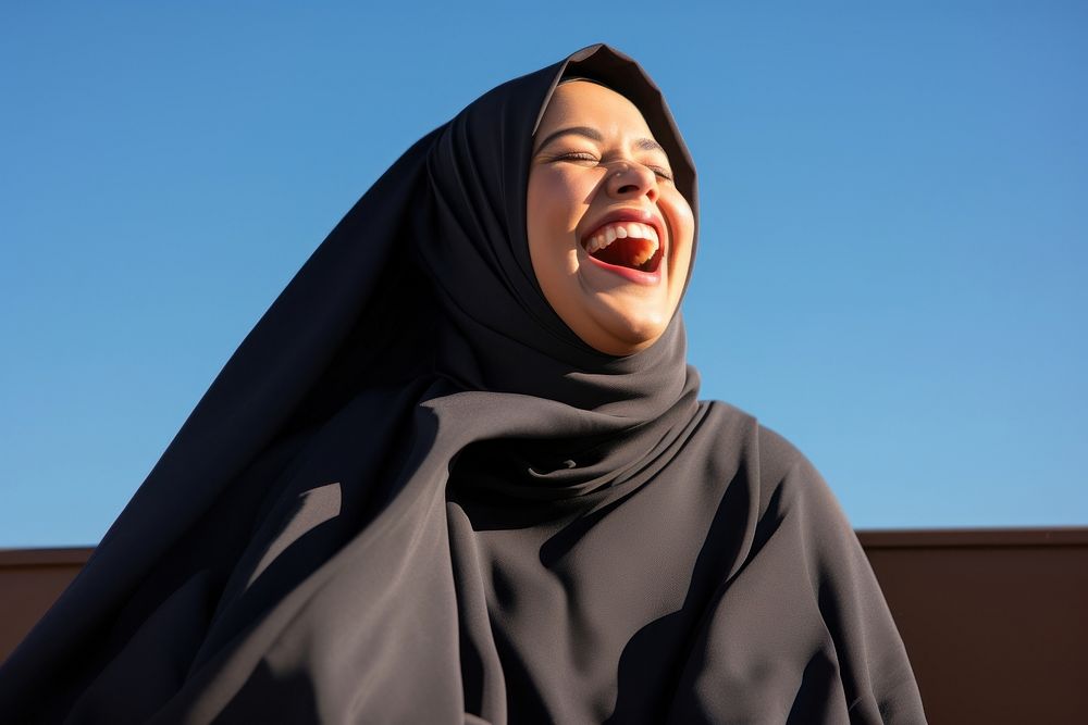 Plus size Middle eastern woman outdoors laughing hijab.