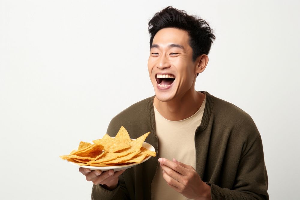 A side view of a man holding plate of chips and biting snack laughing eating adult. AI generated Image by rawpixel.