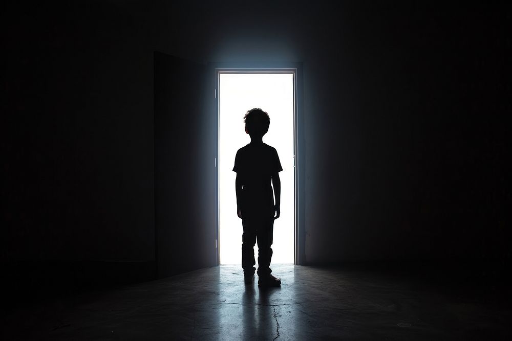 Young boy silhouette standing light black.