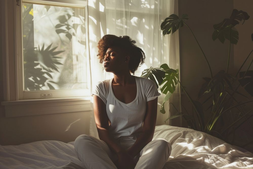 Black woman bed bedroom sitting.