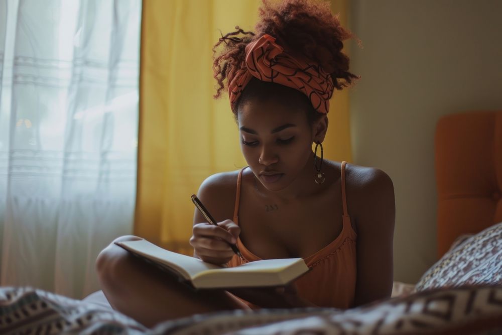Black woman reading bedroom writing.