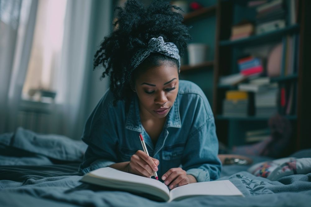 Black woman writing reading bedroom.