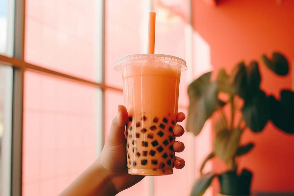 Hand holding a bubble tea drink refreshment disposable.