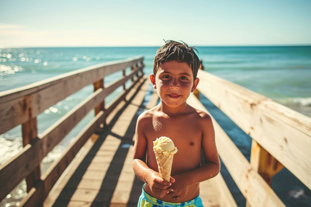 Latino boy holding an ice cream on a boardwalk against ocean background vacation summer child. AI generated Image by…
