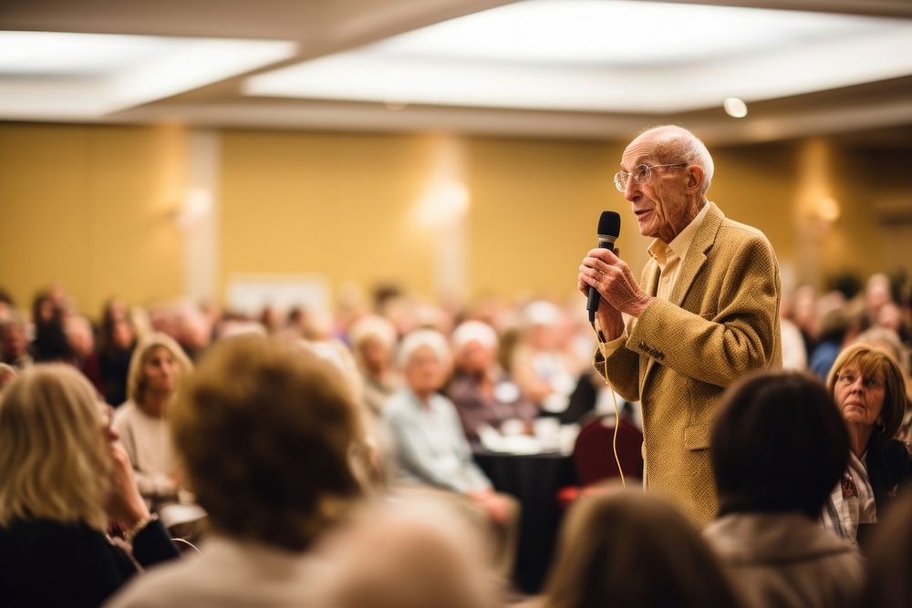 Elderly gentleman giving a motivational speech at a community event audience microphone adult. AI generated Image by…